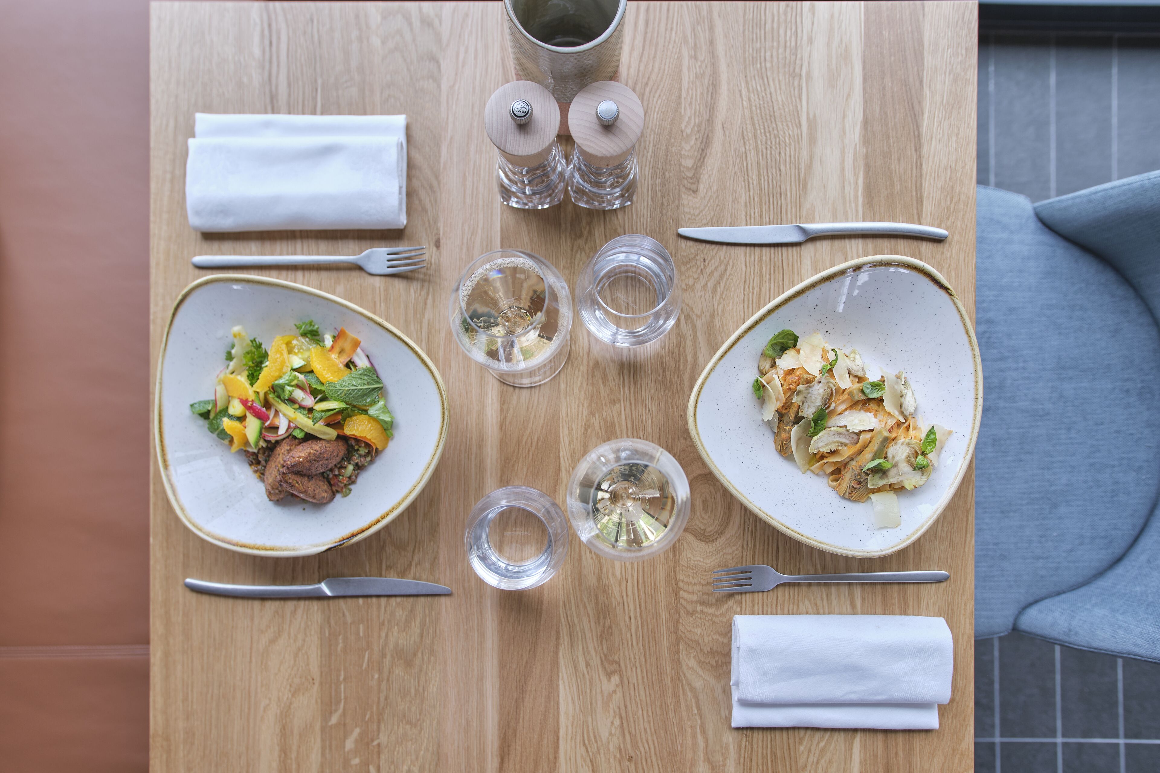Une table à manger avec deux assiettes de nourriture, des couverts et des verres.