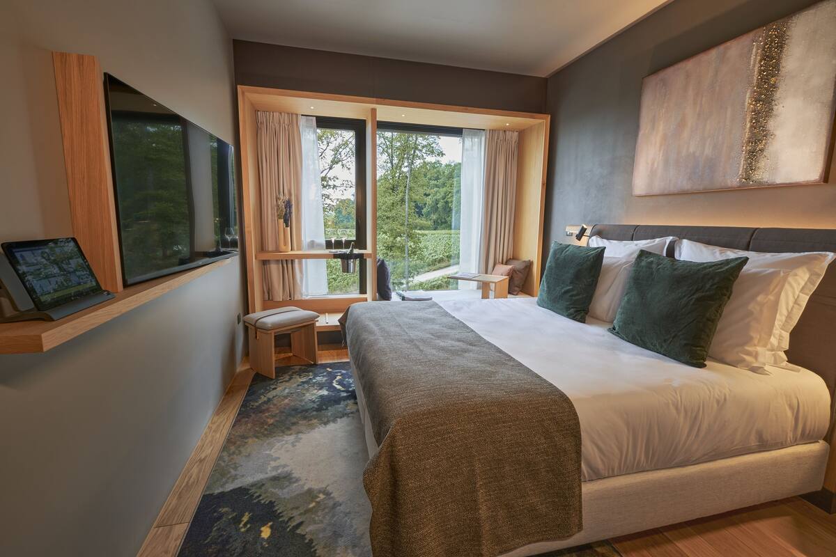 Een moderne hotelkamer met een groot bed, een bureau en een raam met gordijnen.