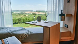 Ein Balkon mit einem Holztisch, zwei Weingläsern und einer Weinflasche.