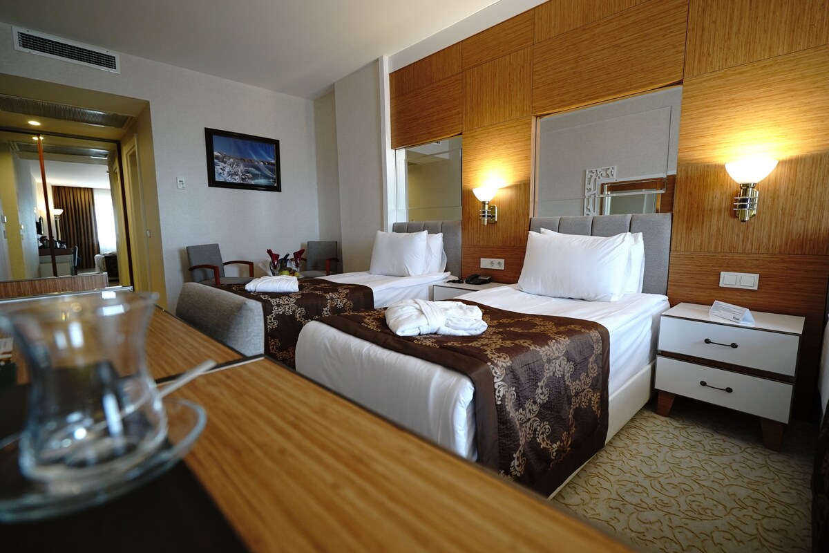A hotel room with two beds, a wooden headboard, a nightstand, a desk, and a mirror.
