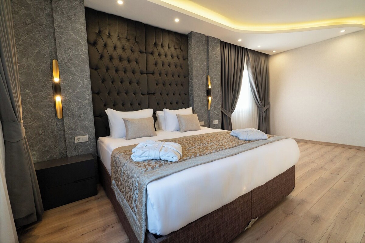 A modern bedroom with a large bed, a tufted headboard, and wall-mounted sconces.