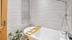 Ein modernes Badezimmer mit freistehender Badewanne, Duschbrause und Handtuchhalter.