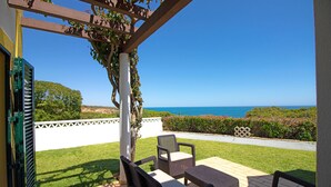 An outdoor patio with wicker furniture and a view of the ocean.