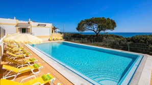 A swimming pool with lounge chairs and a view of the sea.