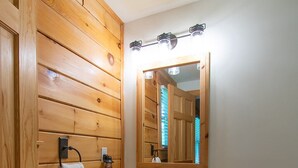 Een houten badkamer met een wastafel, spiegel en toilet.