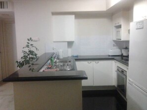 Kitchen area with central island, white cabinetry, and black countertop.