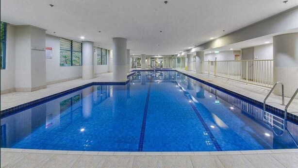 En inomhuspool med kristallklart blått vatten, omgiven av väggar med fönster och ett kaklat golv.