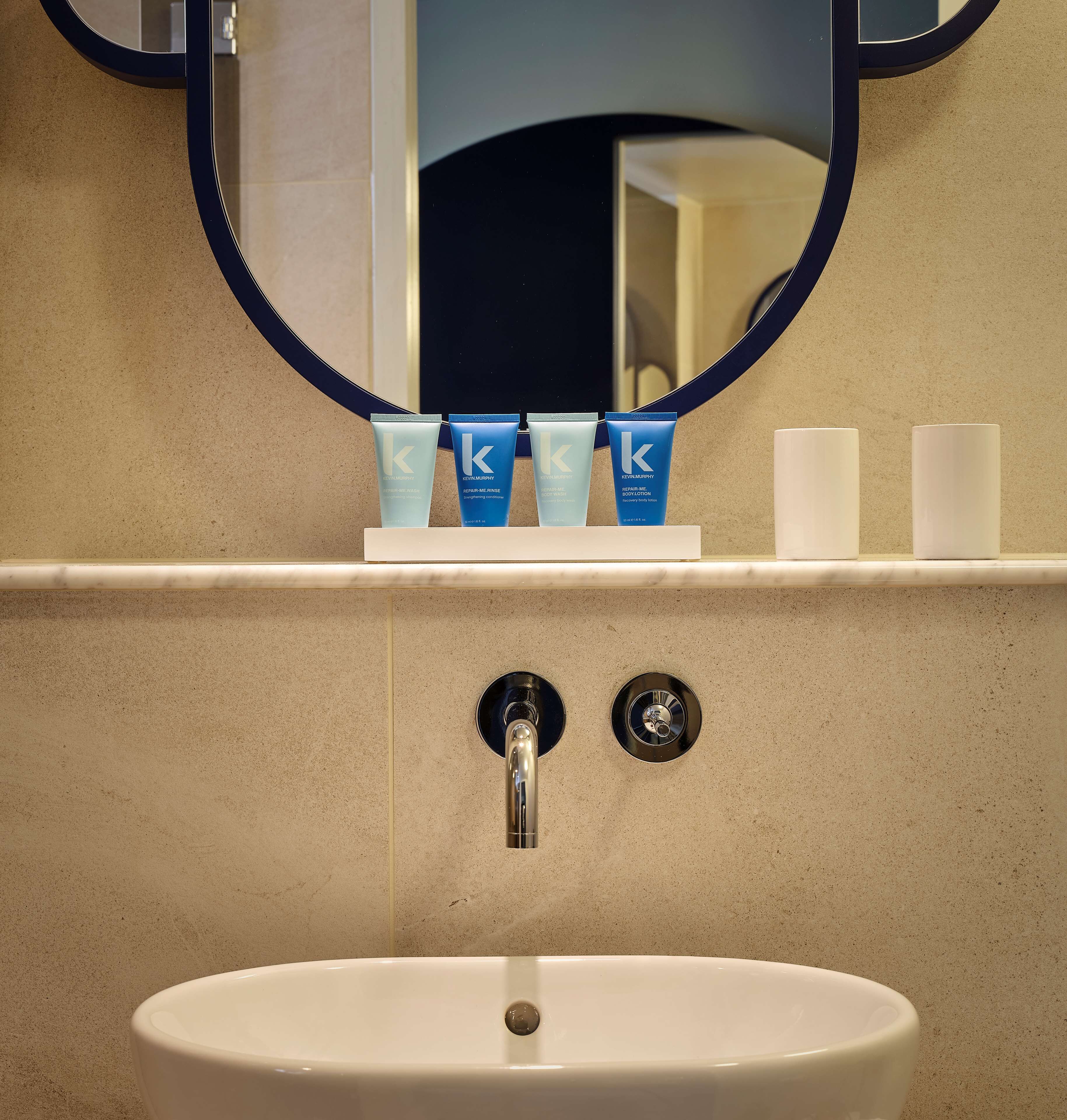 A bathroom with a sink, mirror, and toiletries.