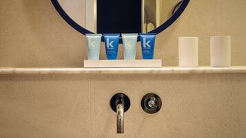 A bathroom with a sink, mirror, and toiletries.