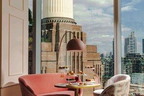 Een moderne kamer met uitzicht op de stad, een ronde tafel met gebak en een groot raam.