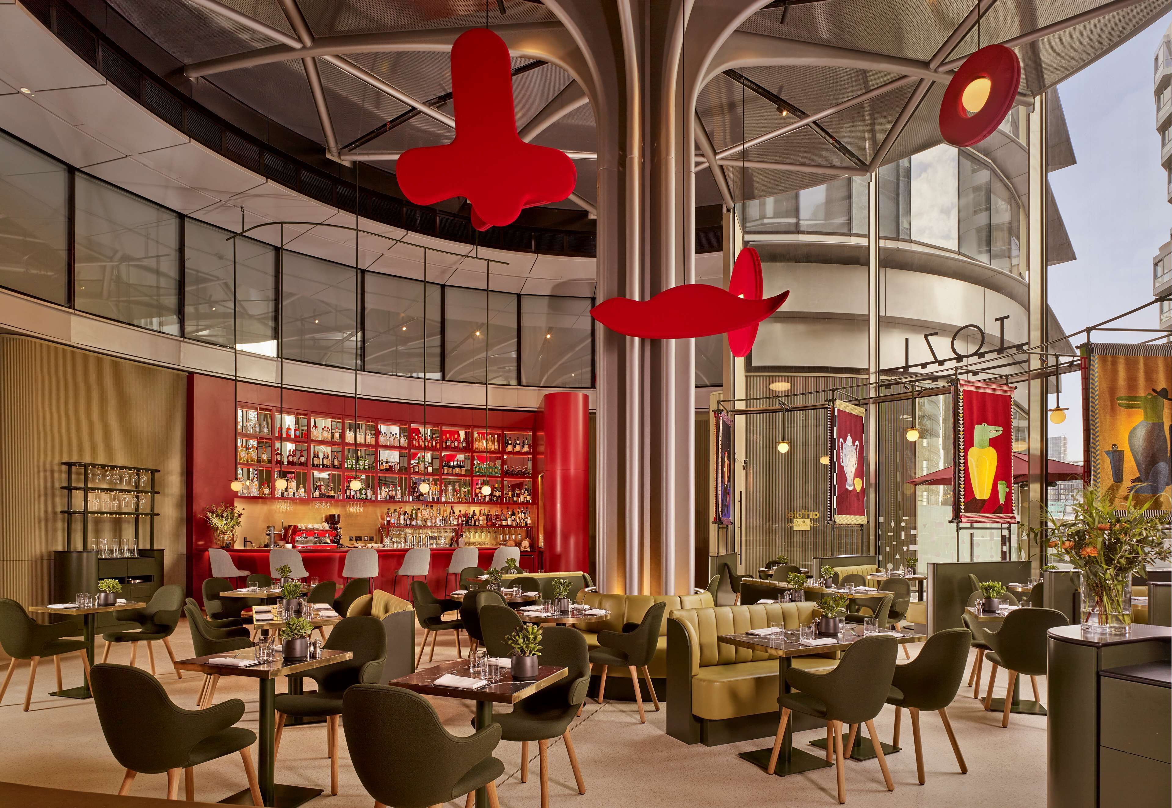 A modern interior with a bar area, seating arrangements, and a large glass facade.