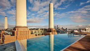 Une piscine à débordement située sur le toit, avec la silhouette de la ville en arrière-plan.