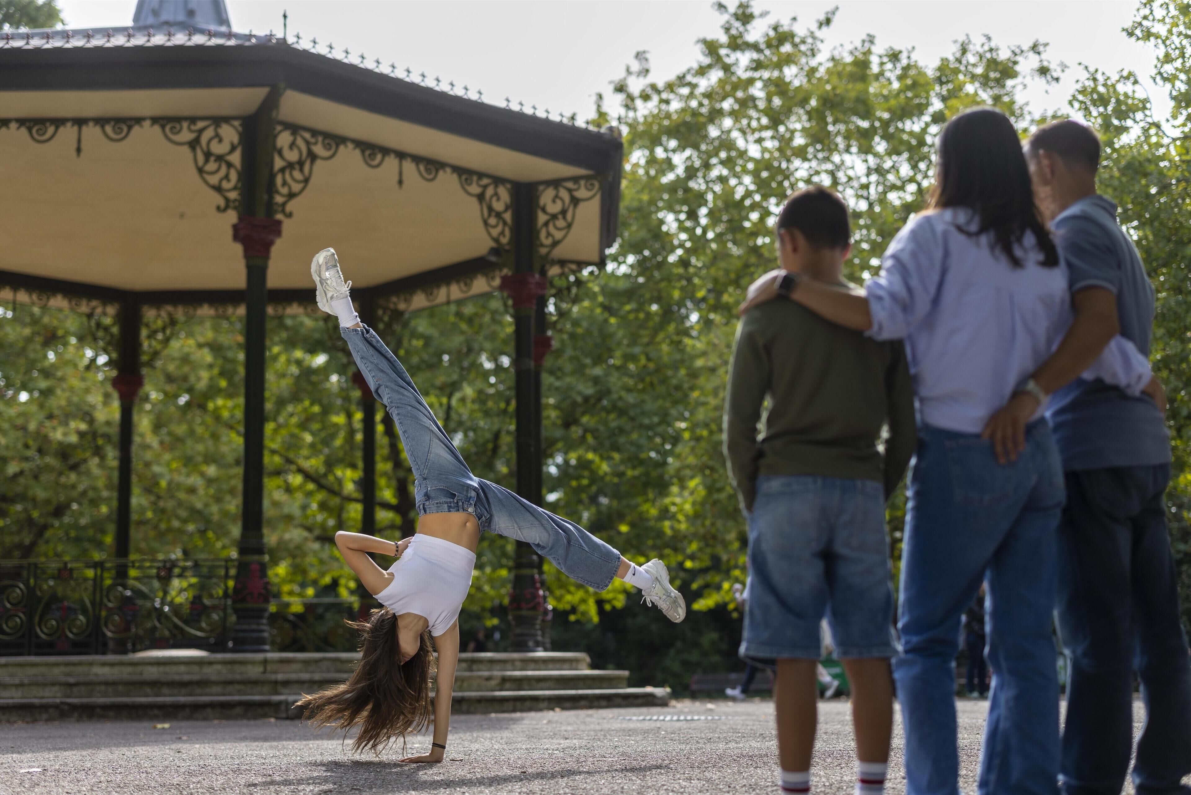A person performing a handstand in front of a gazebo.