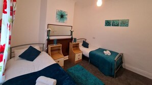 Camera da letto con due letti, un comodino, una cassettiera e uno specchio. Sono presenti opere d'arte a parete e una lampada a soffitto.