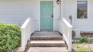A house with a green door, white railings, and a small porch with steps.