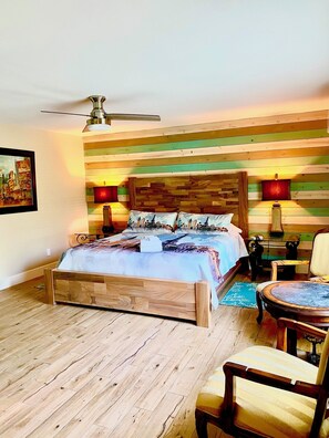 A bedroom with a wooden bed, a ceiling fan, a wooden headboard, a nightstand, a chair, and a small table. - Coast Oaks Cottage 6 1 Bedroom Cottage by RedAwning (Rockport)