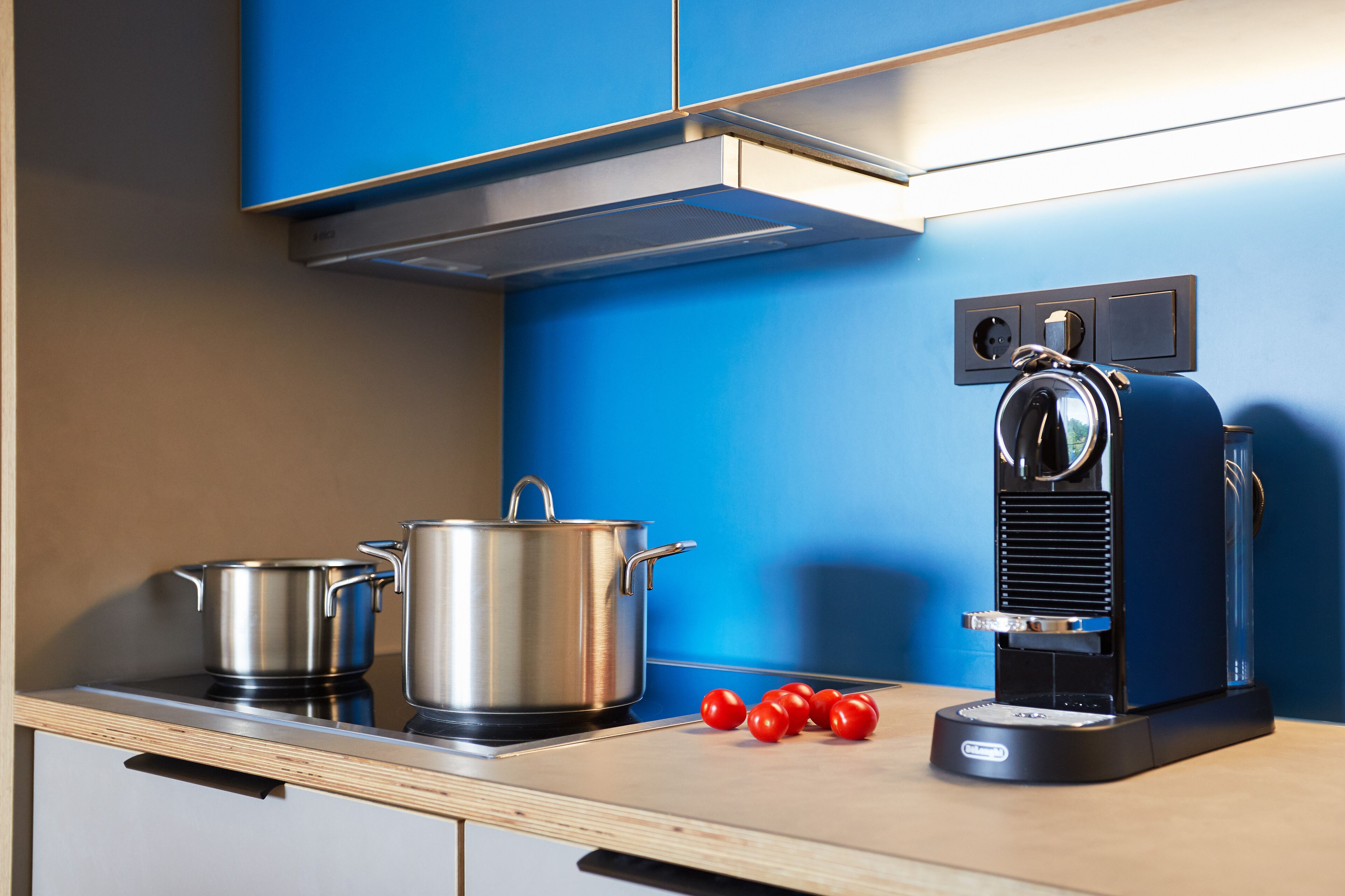 A kitchen with stainless steel pots, a coffee machine, and a wooden countertop.