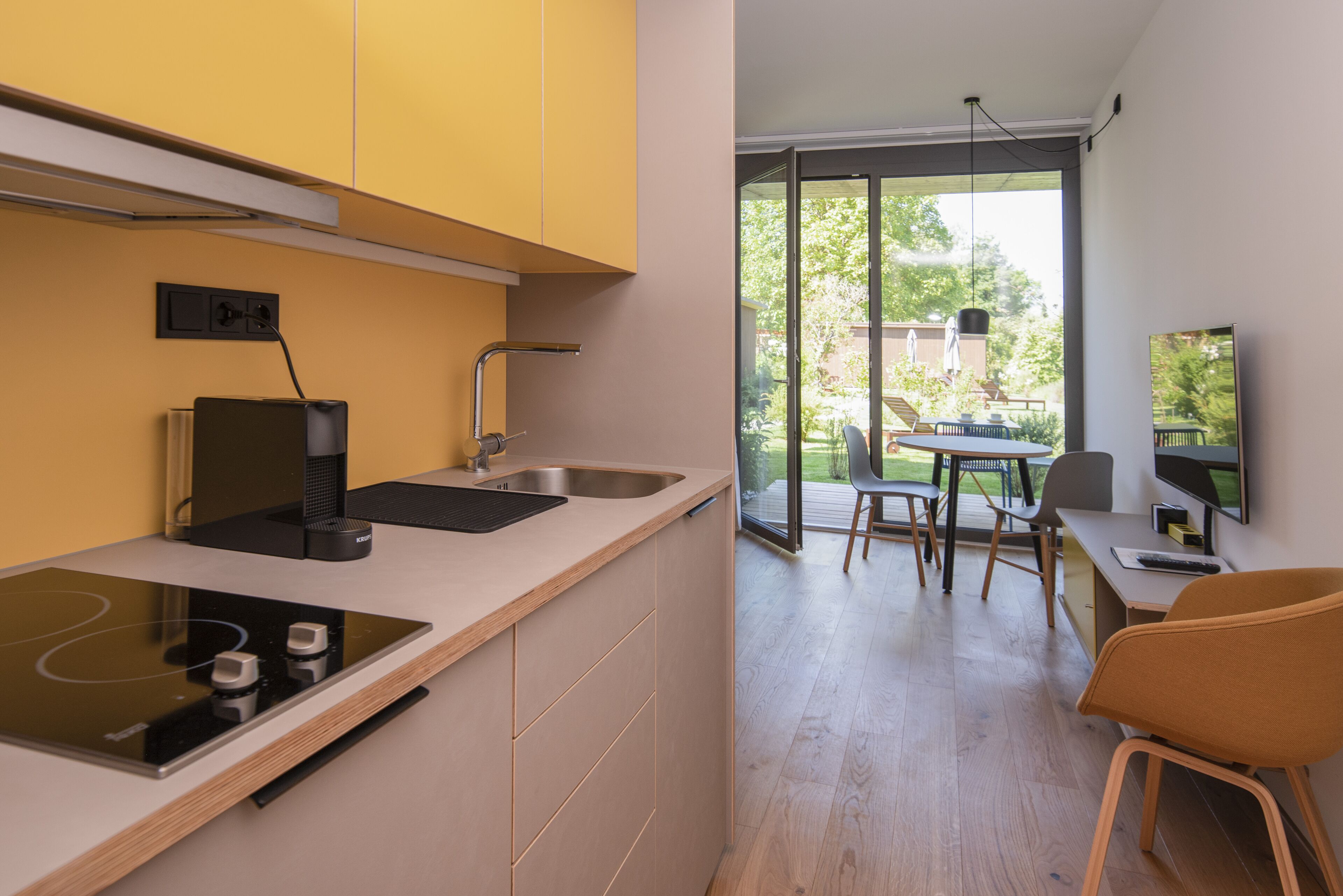 A modern kitchen with a built-in stove, a sink, and a dining area with a table and chairs.