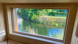 Una cabaña de madera con un ventanal grande que da a un río y follaje.