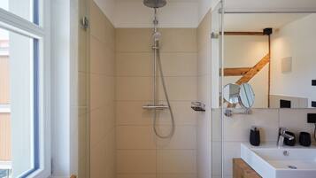A modern bathroom with a shower, a sink, and a mirror.