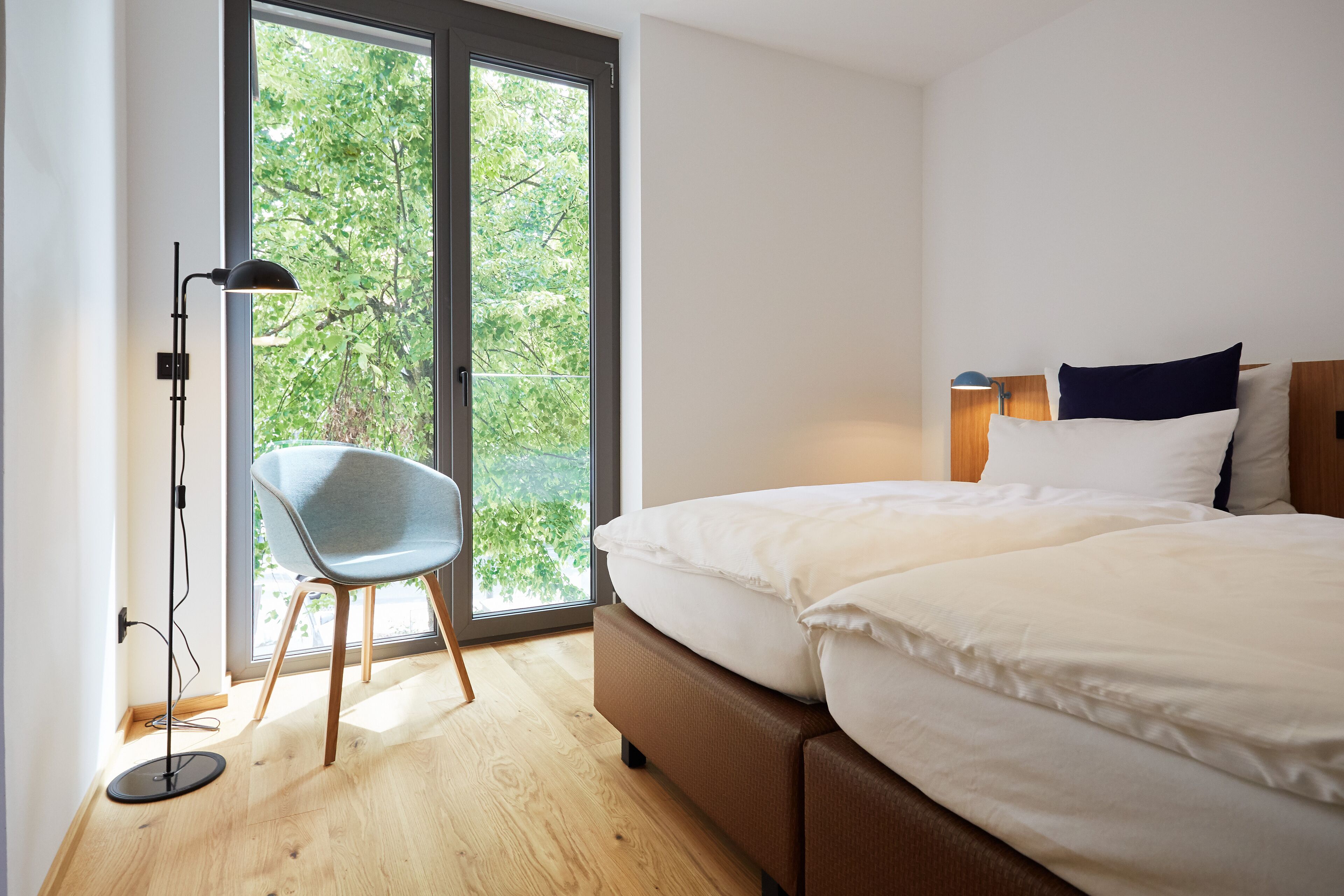 A modern bedroom with a large bed, a chair, and a floor lamp.