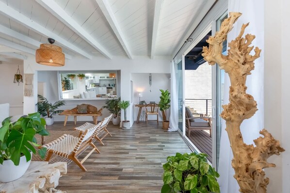 A modern interior with a wooden floor, woven chairs, potted plants, and a large wooden sculpture. - Casa del Mar by Oraklus (Malibu)