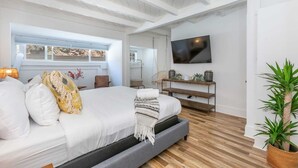 Une chambre à coucher moderne avec un lit, une télévision, une fenêtre et une plante.