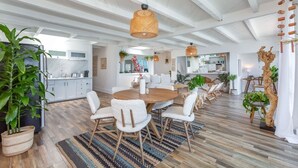 Un vaste espace de vie agrémenté d’une table ronde en bois, de fauteuils blancs à la texture douce et d’un tapis à rayures.