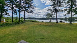 A grassy area with trees and a body of water in the background.