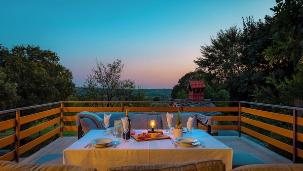 An outdoor dining area with a table set for two, surrounded by wooden railings, overlooking a scenic landscape. - House Manda Adriatic (Piramatovci)