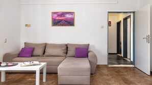 A living room with a sofa, ottoman, and a table with a book and glasses. - House Manda Adriatic (Piramatovci)