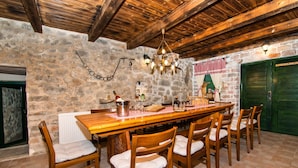 Un coin repas rustique avec une table et des chaises en bois, des murs en pierre et un lustre.