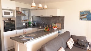 A modern kitchen with a central island, a built-in oven, a coffee machine, and a sink.