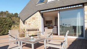 A house with a patio area featuring outdoor furniture and a sliding glass door leading to an interior space.