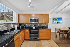 A modern kitchen with wooden cabinets, a stainless steel stove, and a black countertop.