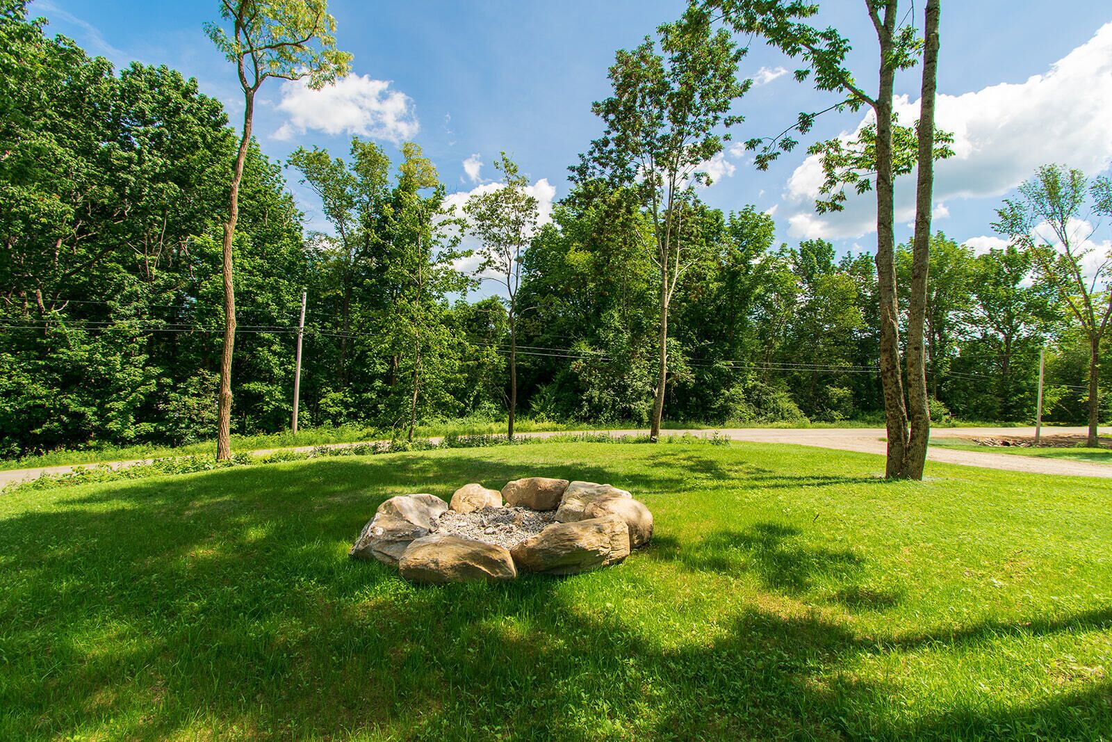 A park with a circular stone structure surrounded by grass and trees.