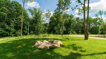 A park with a circular stone structure surrounded by grass and trees.