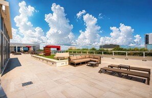 An outdoor terrace with seating arrangements and a view of the sky.