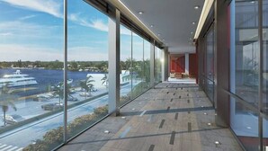 A modern corridor with large windows overlooking a marina and water.