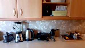 A kitchen with a coffee maker, kettle, and other appliances on the counter. - Immaculate 2-bed Apartment (Paiania)