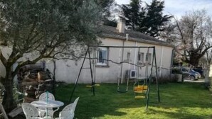 A backyard with a swing set, a small table with chairs, and a tree. - CHARMING 2 ROOM APARTMENT WITH ALL COMFORTS + AIR CONDITIONING (Tornac)