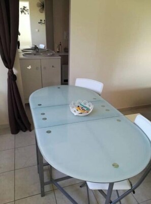 A dining table with four chairs, a small basket with items, and a kitchen area in the background.