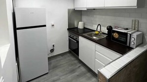 A modern kitchen with white cabinets, a black countertop, a built-in oven, a sink, and a microwave.