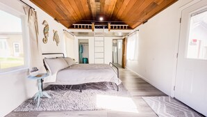 A bedroom with a bed, a small table, a rug, and a wooden ceiling. - Indoor heated pool ocean views. Fishing short walk away. Pet Friendly!  (Smith River)