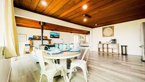 A dining area with a wooden ceiling, white chairs, and a round table with blue and white patterned tableware. - Indoor heated pool ocean views. Fishing short walk away. Pet Friendly!  (Smith River)
