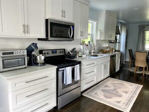 A modern kitchen with white cabinetry, a built-in oven, a microwave, and a coffee maker. - Blue Door: Walk to Avondale, Dog-Friendly w Yard (Birmingham)