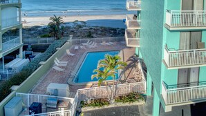 Zona de piscina con sillones reclinables, una piscina pequeña y vistas a la playa.