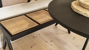 A black table with woven placemats and a woven basket on it.