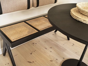 Een zwarte tafel met geweven placemats en een geweven mand erop.