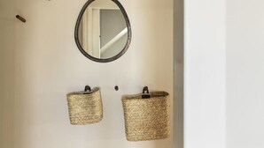 A wall-mounted mirror with two woven baskets below it.